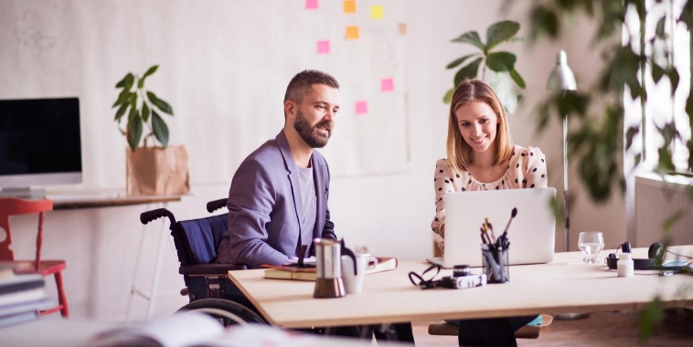 Two office workers looking at laptop